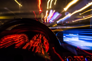 Car speeding down a highway road at night. 